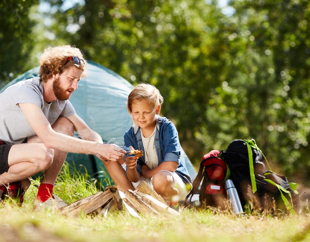 dad and daughter starting a campfire