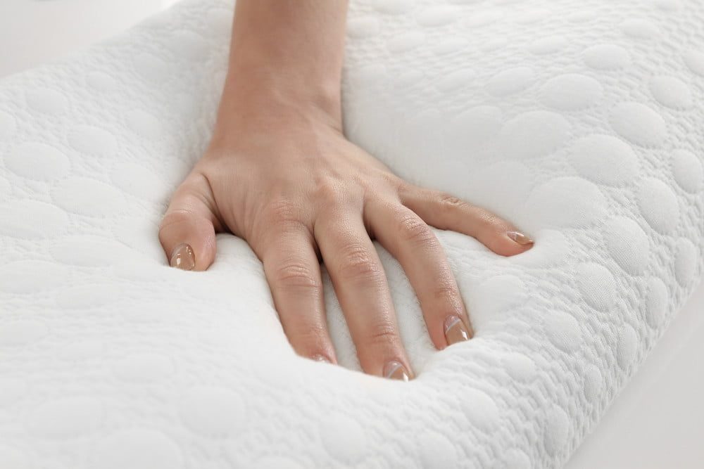 Woman's hand pressing into memory foam pillow