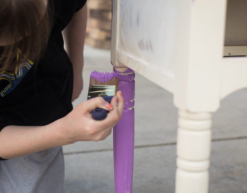 closeup of a woman's hand painting a table leg