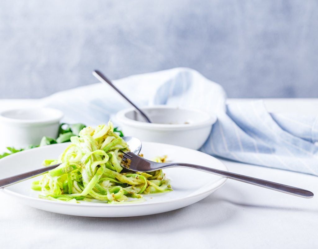 pesto zoodles with chicken on a white plate