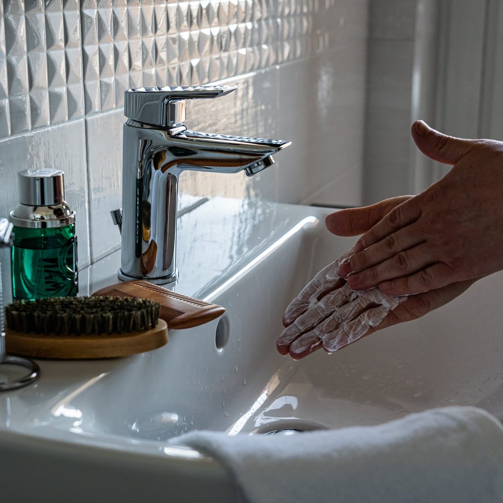 person washing hands in bathroom sink