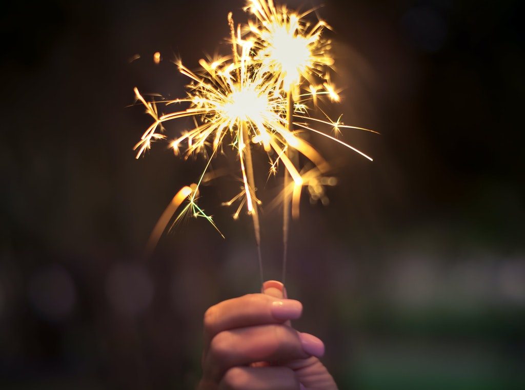 A hand holding a sparkler at night