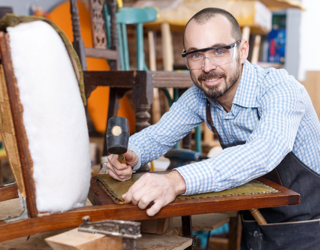 man reupholstering a chair