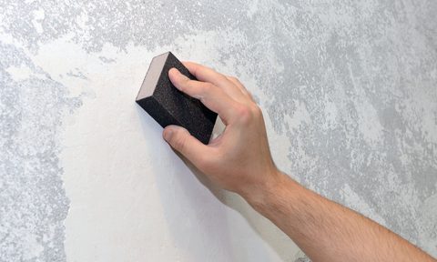 Person sanding down uneven walls