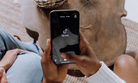 Hands holding phone with TikTok logo