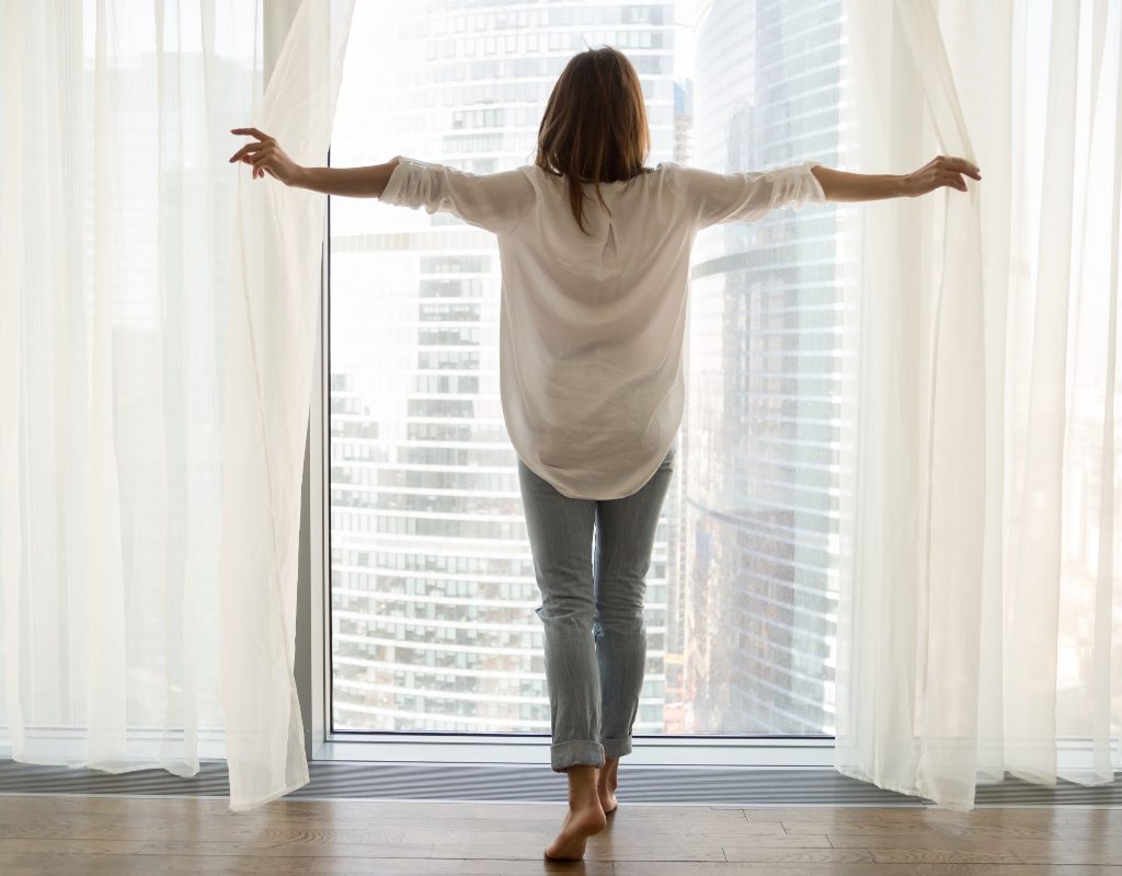 woman opening sheer curtains
