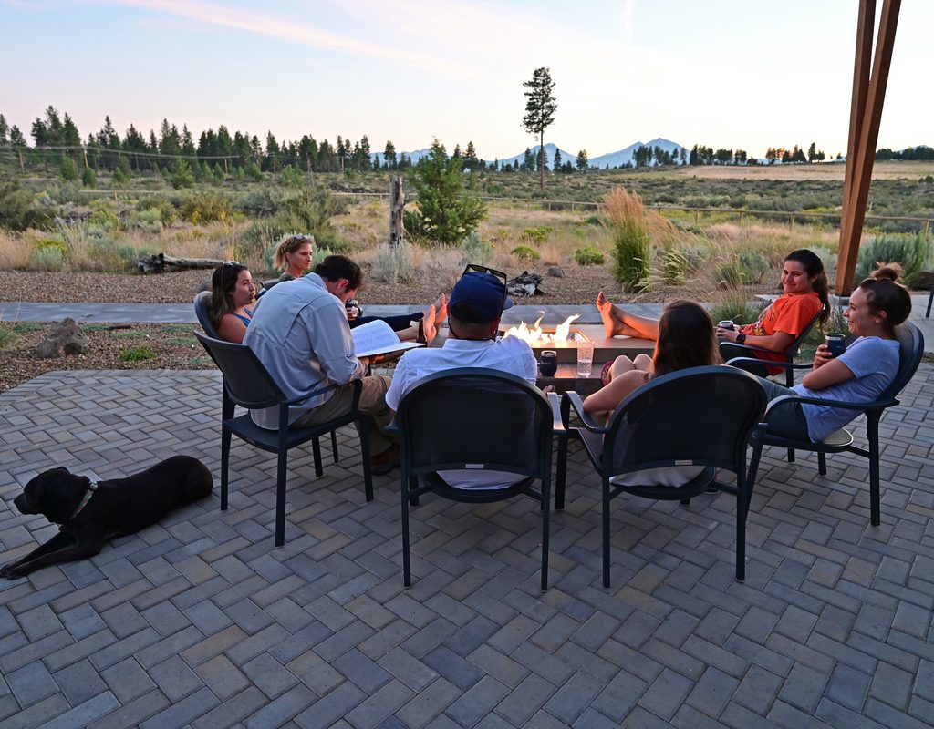 six friends sitting around a fire pit in the evening