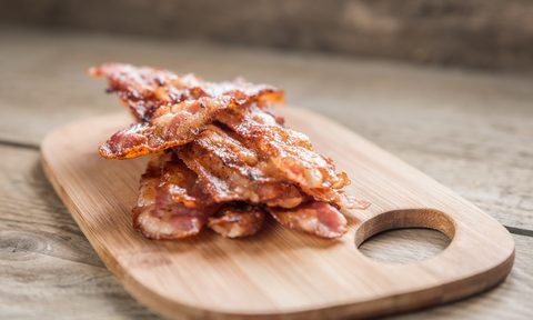 crispy bacon stacked on a wood board on counter