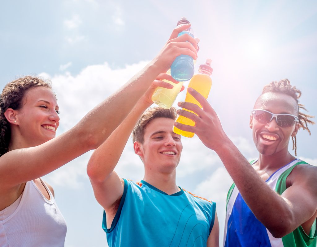 Athletes taking a break after training drinking colorful energy drink or sports drinks