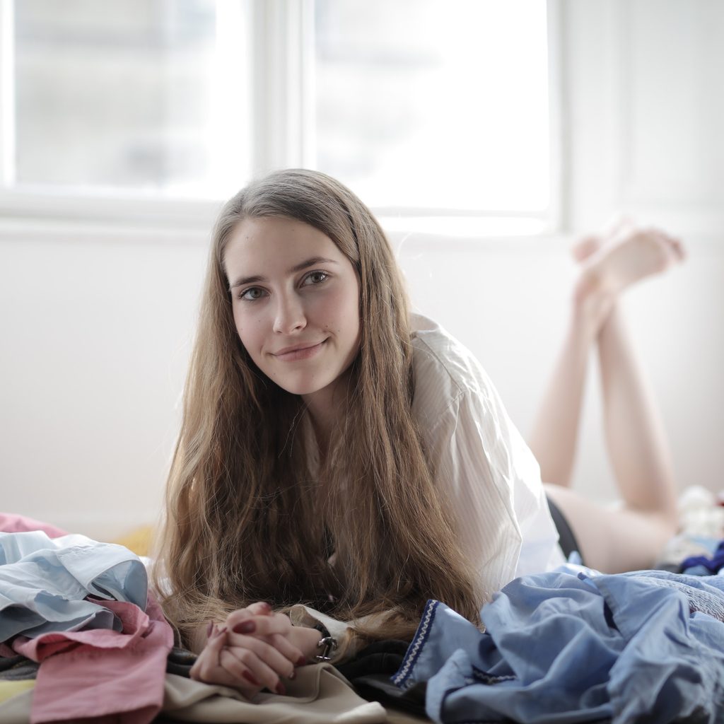 Girl surrounded by clutter on bed