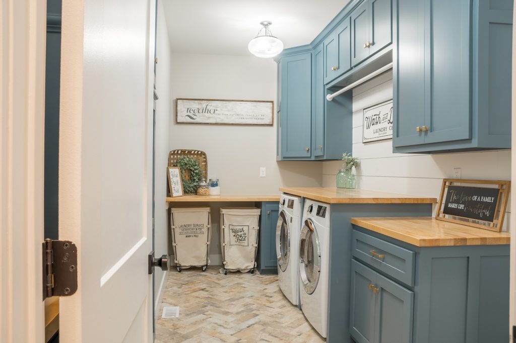 Well lit laundry room with blue cabinets