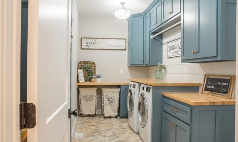 Well lit laundry room with blue cabinets