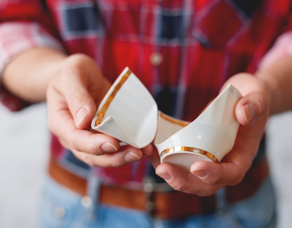 man in plaid shirt holding broken mug