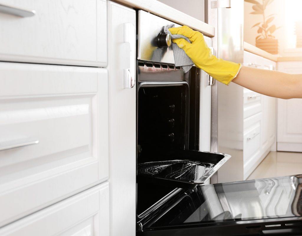 gloved hand cleaning an oven