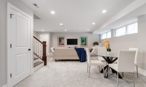 Finished basement seating area with white walls and carpet