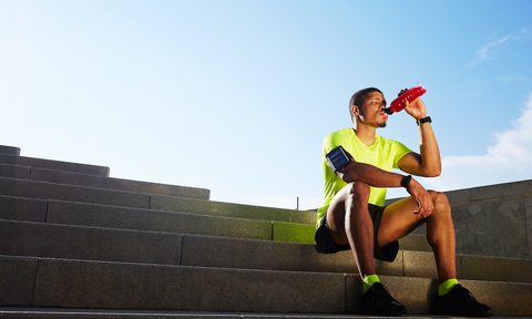 Runner seated on the steps having a sports drink