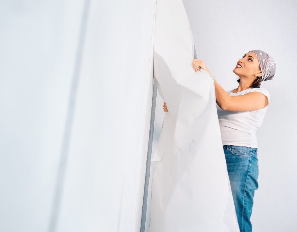 woman removing wallpaper from the wall