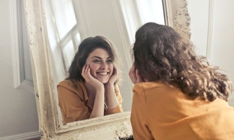 Woman looking in antique mirror