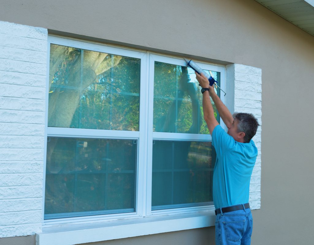 Man caulking around window
