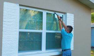 Man caulking around window