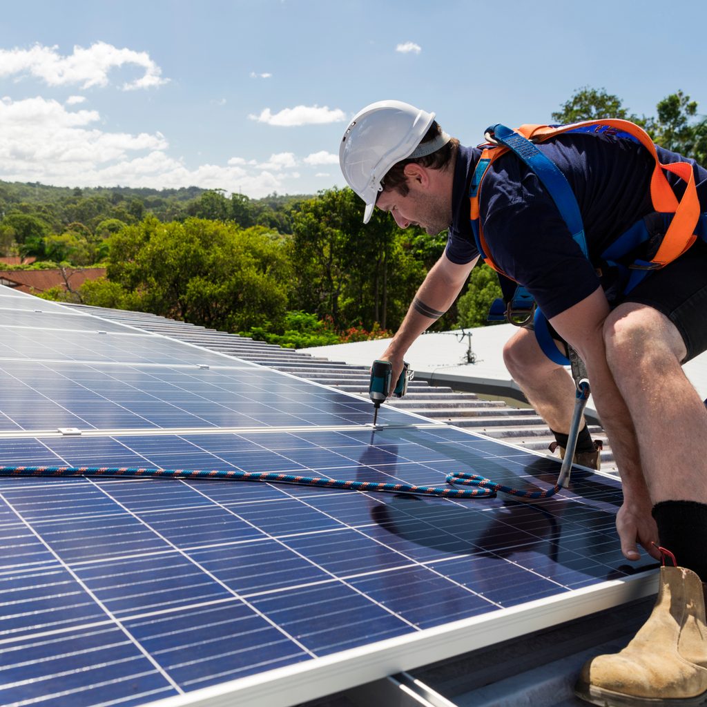 Worker installing solar panels on roof