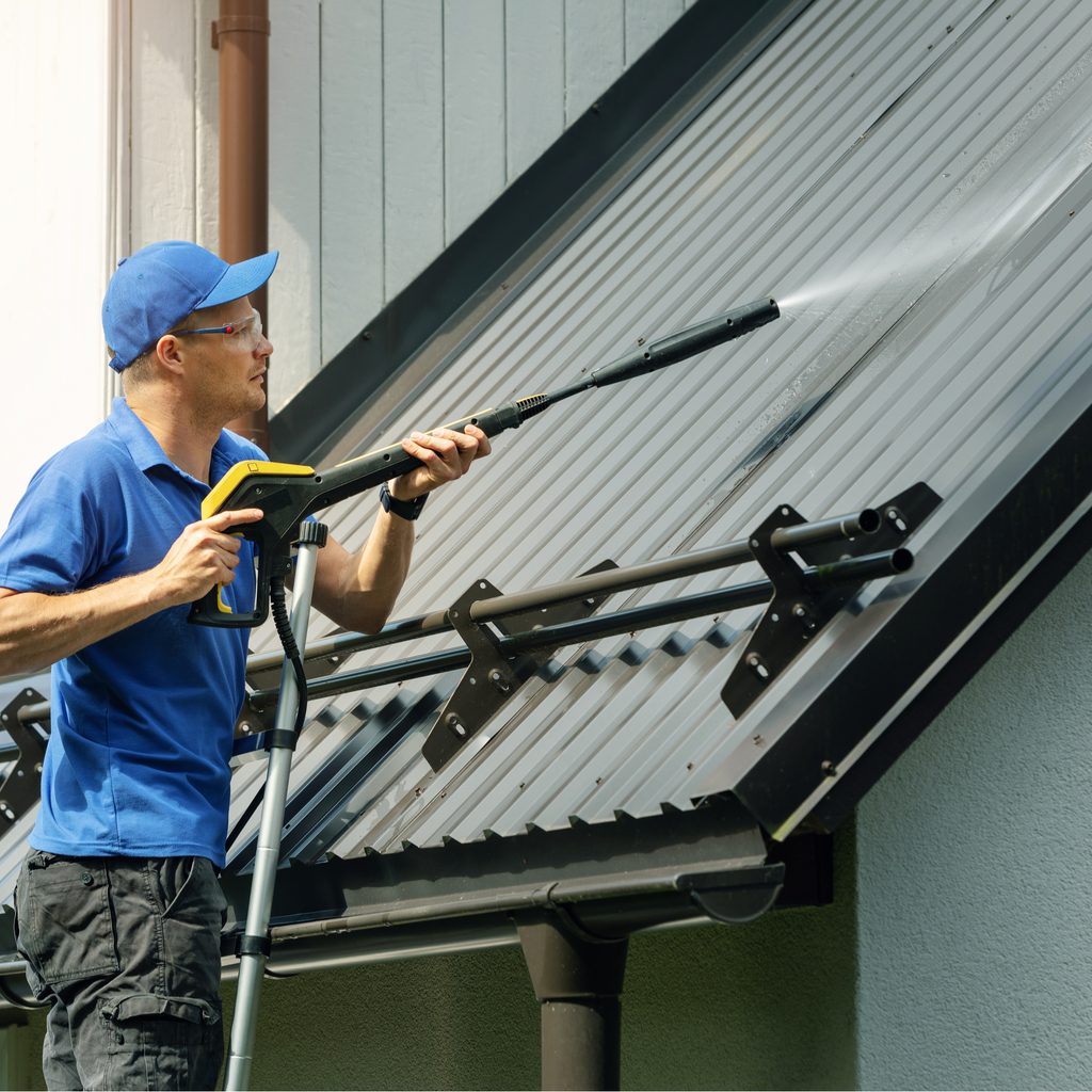 Man spraying roof with power washer