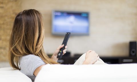 Woman with remote watching TV on couch