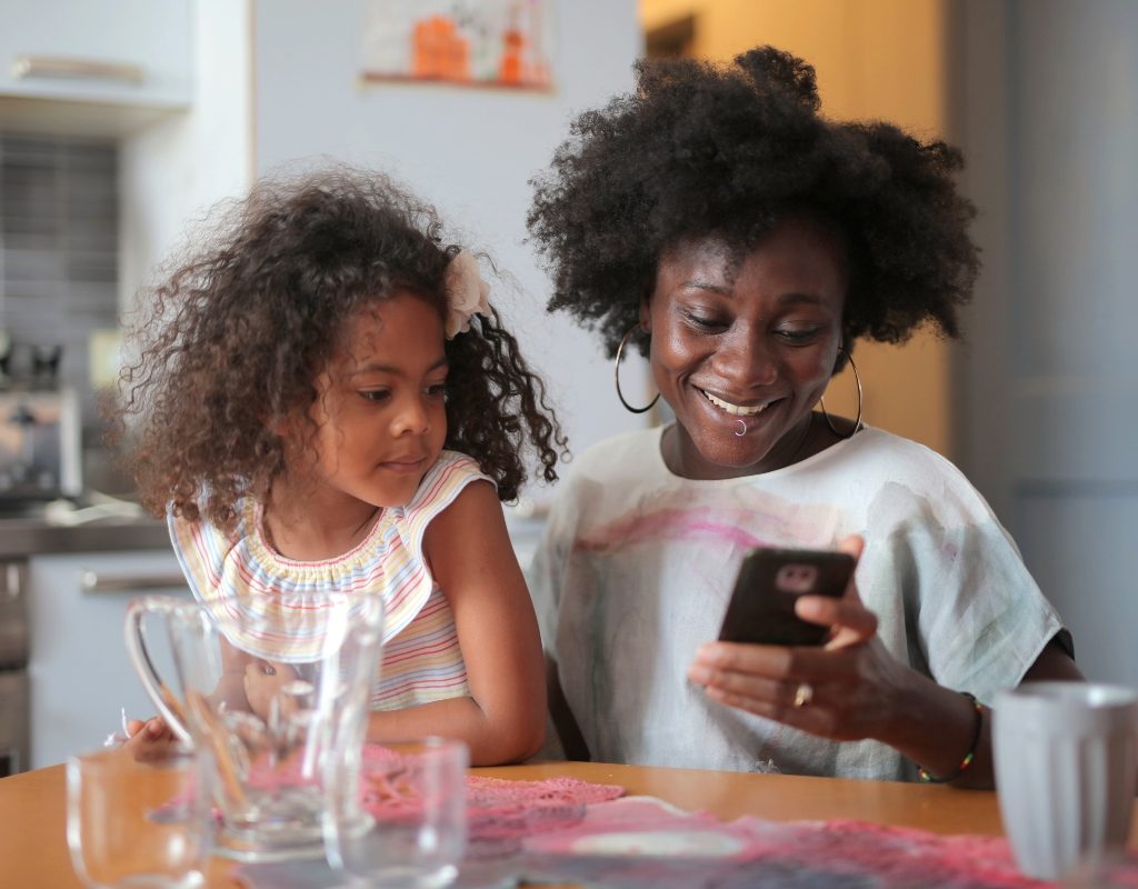 young girl and her mom using iphone while cooking