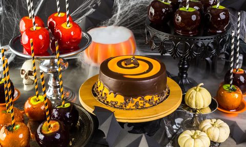 Table with colored candy, apples, and cake for Halloween party