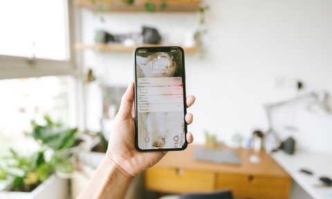 person holding new iphone in office space