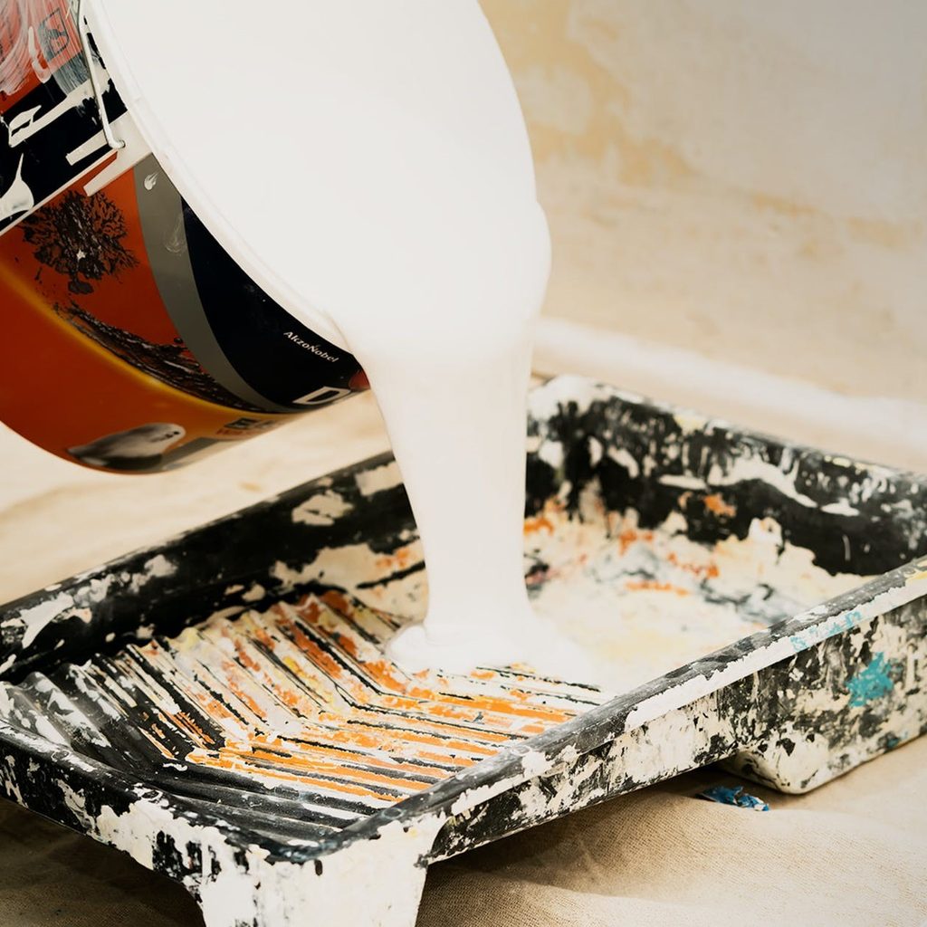 pouring white paint into tray