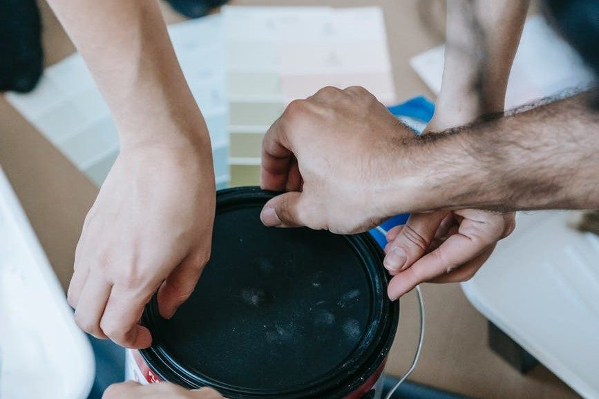 hands covering paint can