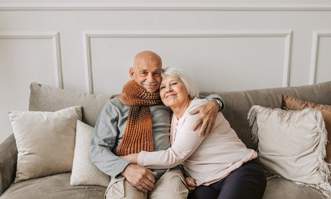 elderly couple sitting on gray couch