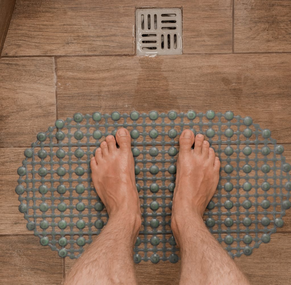 Bath mat and shower drain on wood-look shower tiles