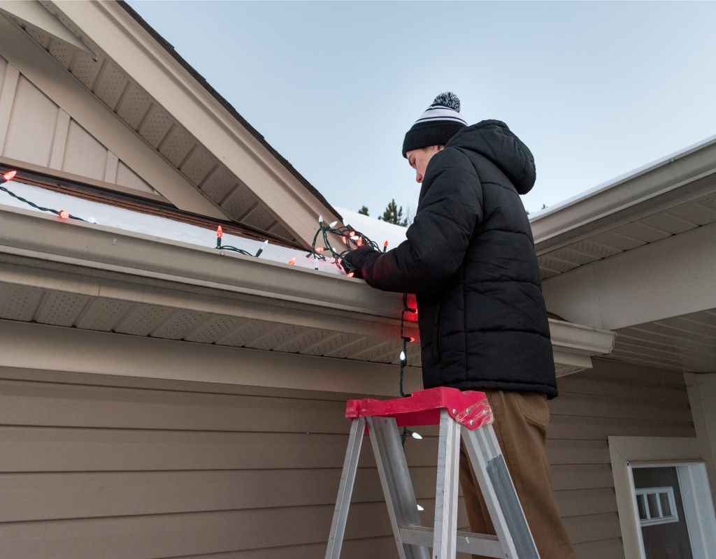 Man hanging Christmas light on the roof