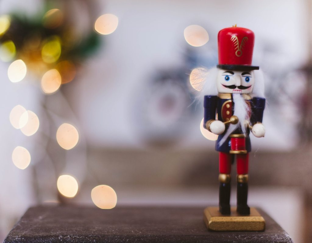 christmas nutcracker sitting on table with lights in the background