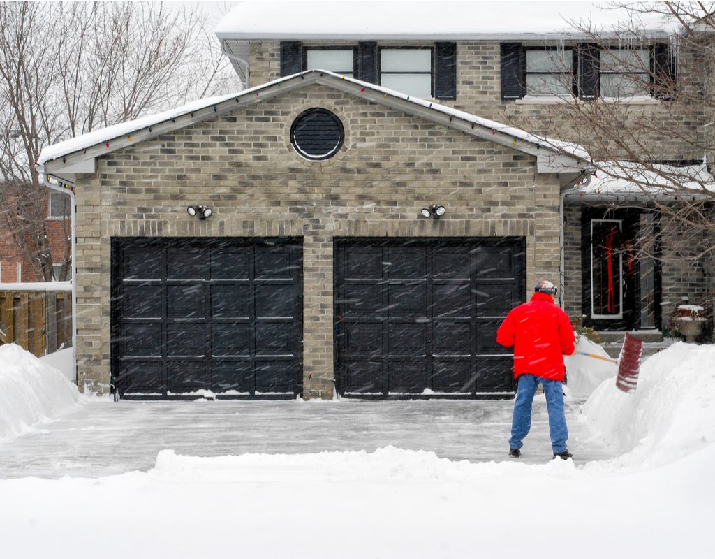 Garage and driveway with man shoveling snow