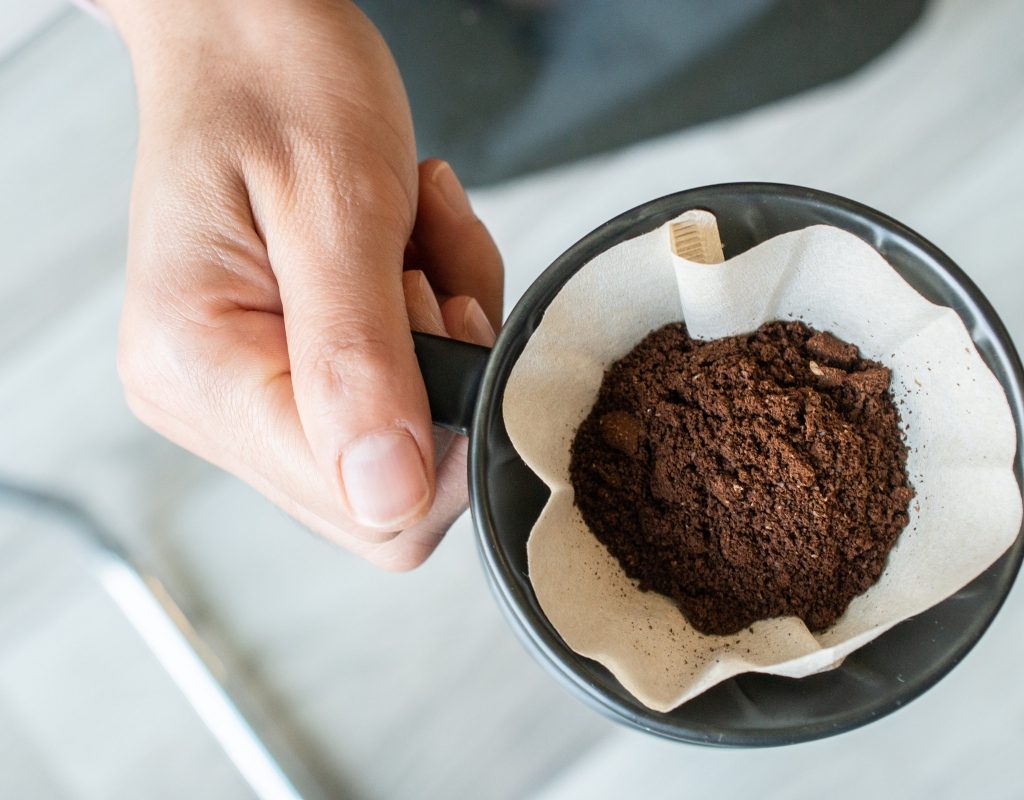 Person holding coffee filter with coffee grounds