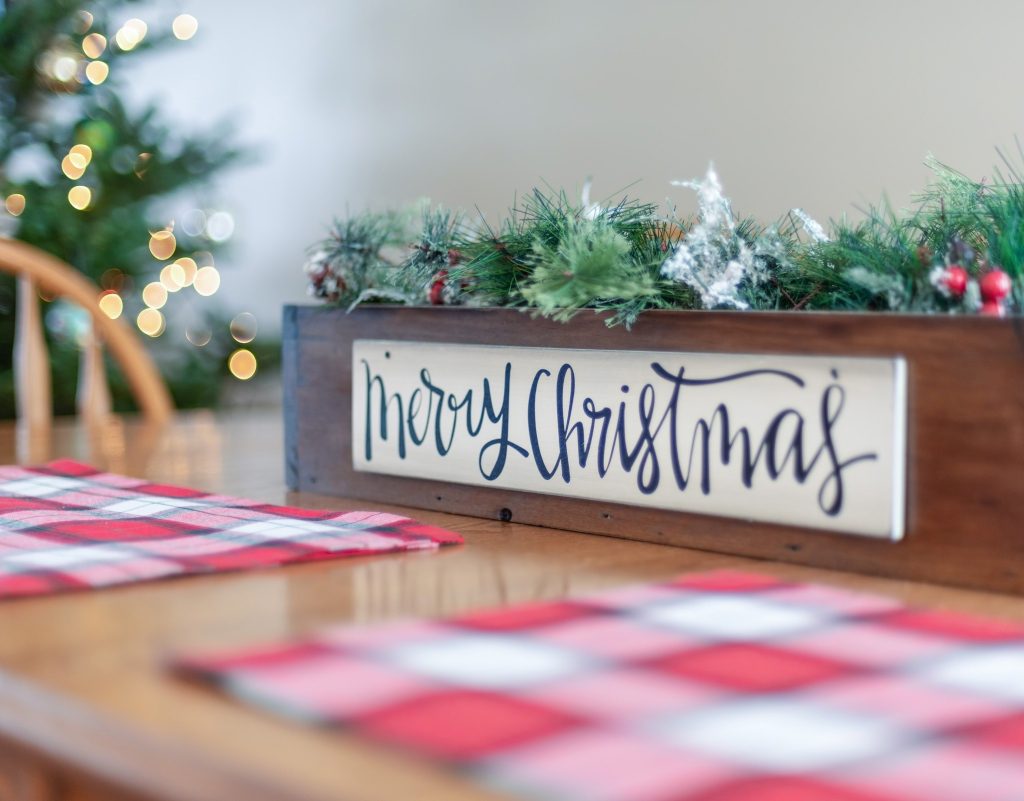 Christmas sign on dining table with plaid placemats