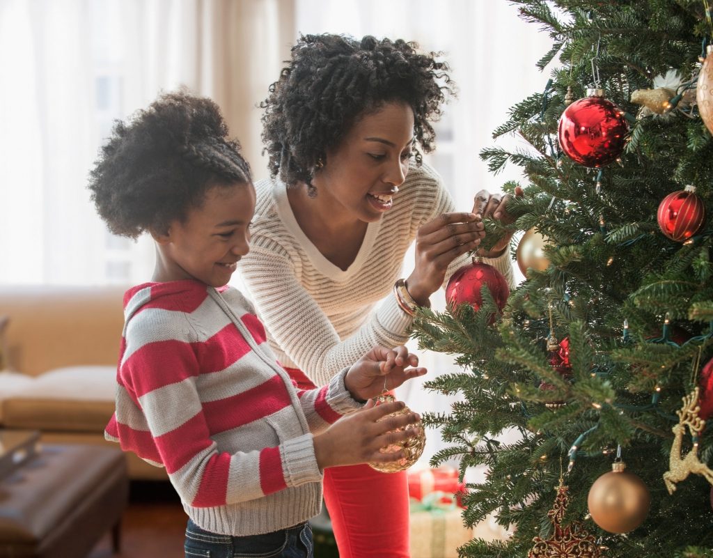 a mother and daughter decorate a christmas tree together