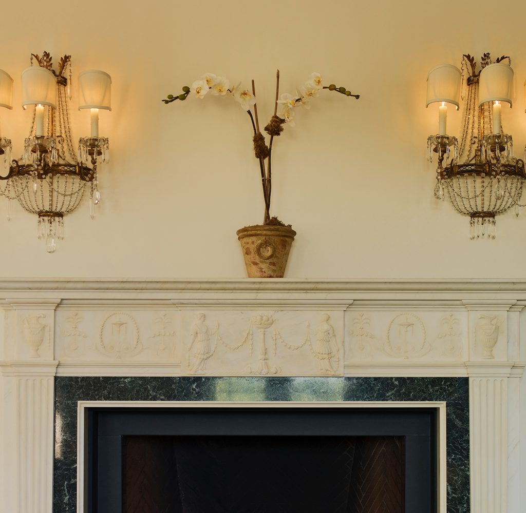 Decluttered mantle with plant and sconces.