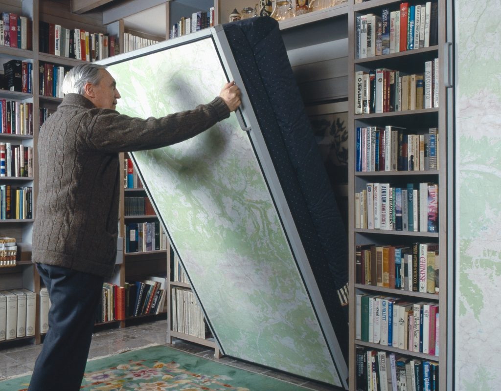 elderly man lowering a murphy bed in home office
