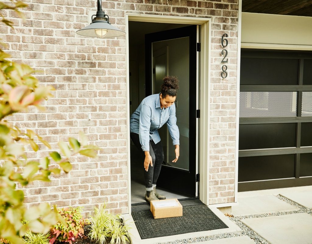 woman picking up a package on her front porch