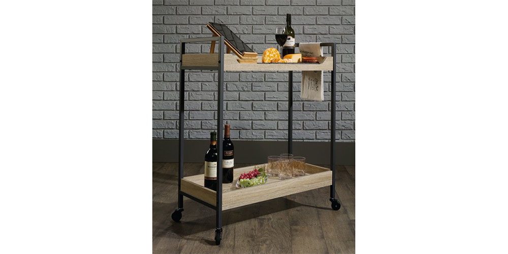 Sauder North Avenue Metal Framed Wood Serving and Bar Cart placed in front of a brick wall.