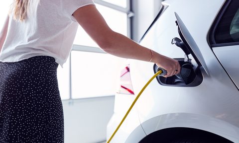 do ev chargers add value to homes close up of woman charging electric vehicle with cable in