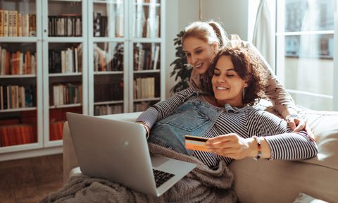 two women using a laptop and credit card for online shopping