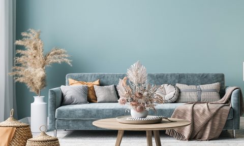 Light blue velvet couch with blankets and slate blue wall