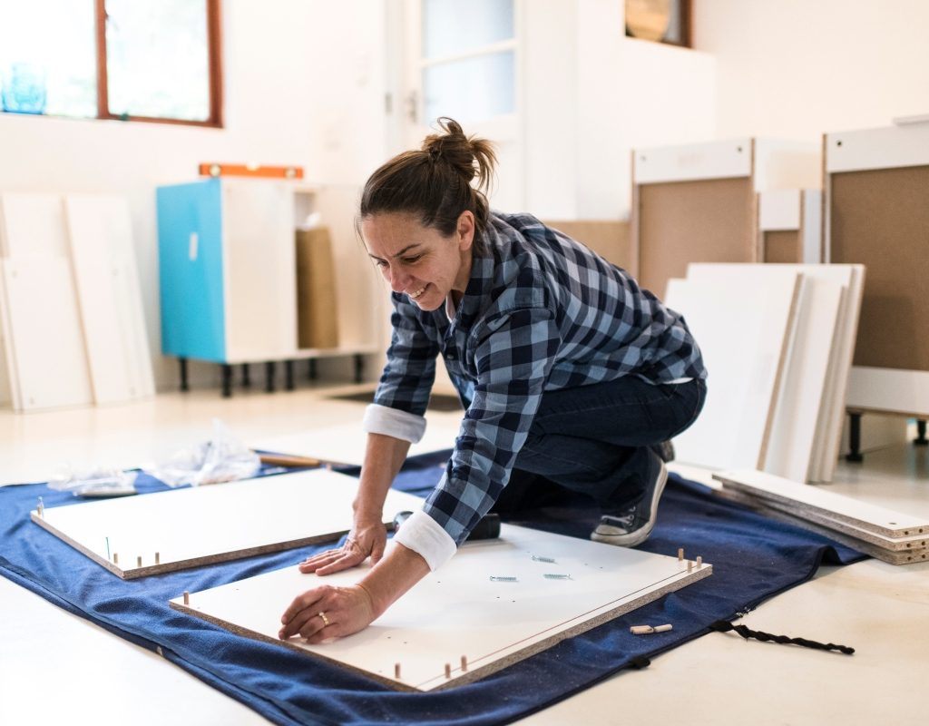 Woman placing kitchen cabinets in remodel