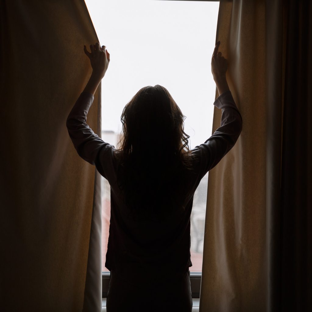 woman closing blackout curtains