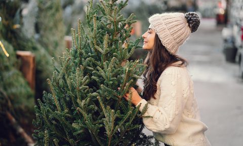 a woman smells a pine scented real christmas tree